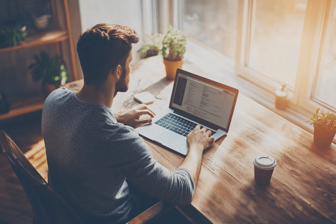 Solo founder working at a laptop with calm focus in a warm, minimal workspace